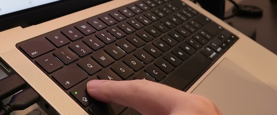 動画3分30秒の実画面。MacBookのCaps Lockキーの緑のランプを指で示している。